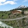A suspended pedestrian bridge over a rushing river leads to a large wooden visitors center